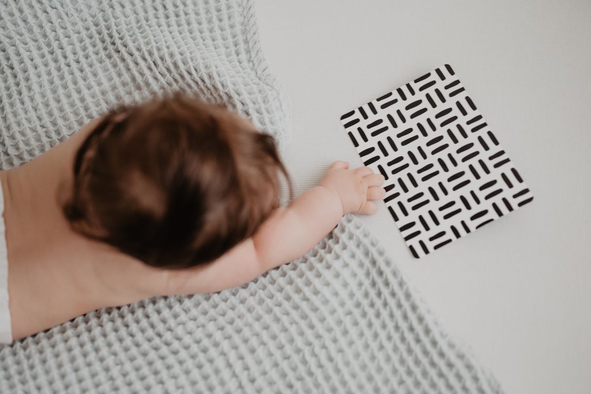 A baby reaching toward a little card