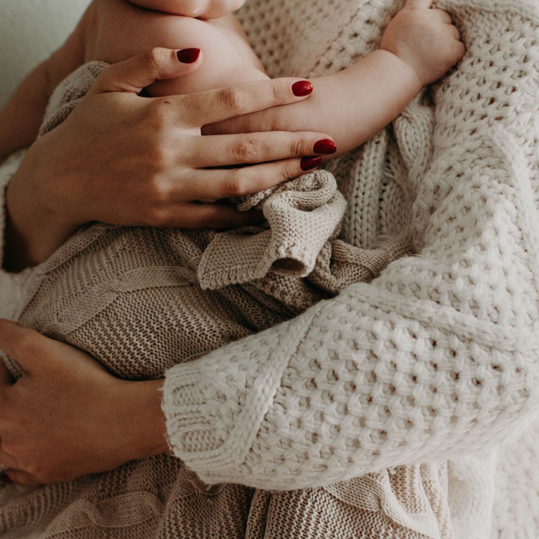 A mother cradling her baby in soft knitwear
